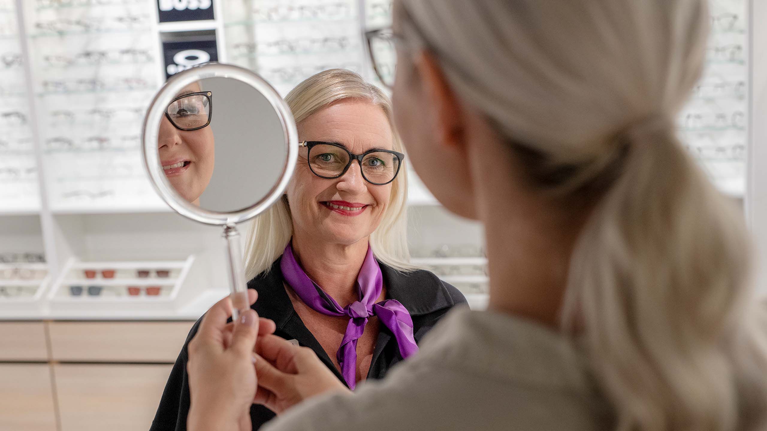 Optikko ja asiakas myym&auml;l&auml;ss&auml; kehyst&auml; sovittaen